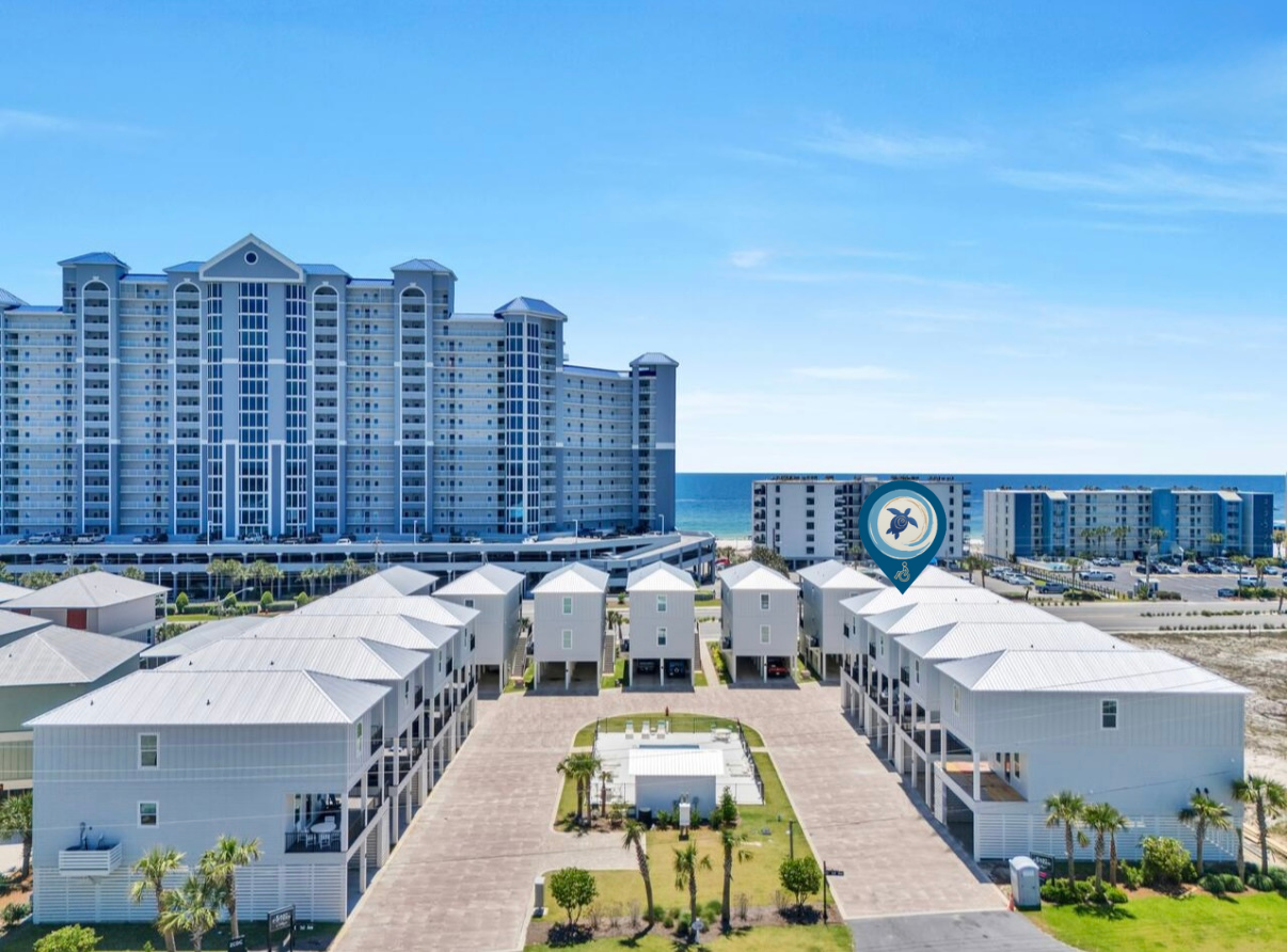 Ariel shot of Beach  resort with white cottages, central pool, and a tall blue high-rise under a clear sky