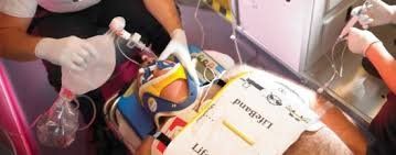 Personal médico atendiendo a una persona en camilla. La persona lleva un collarín y equipo médico conectado.