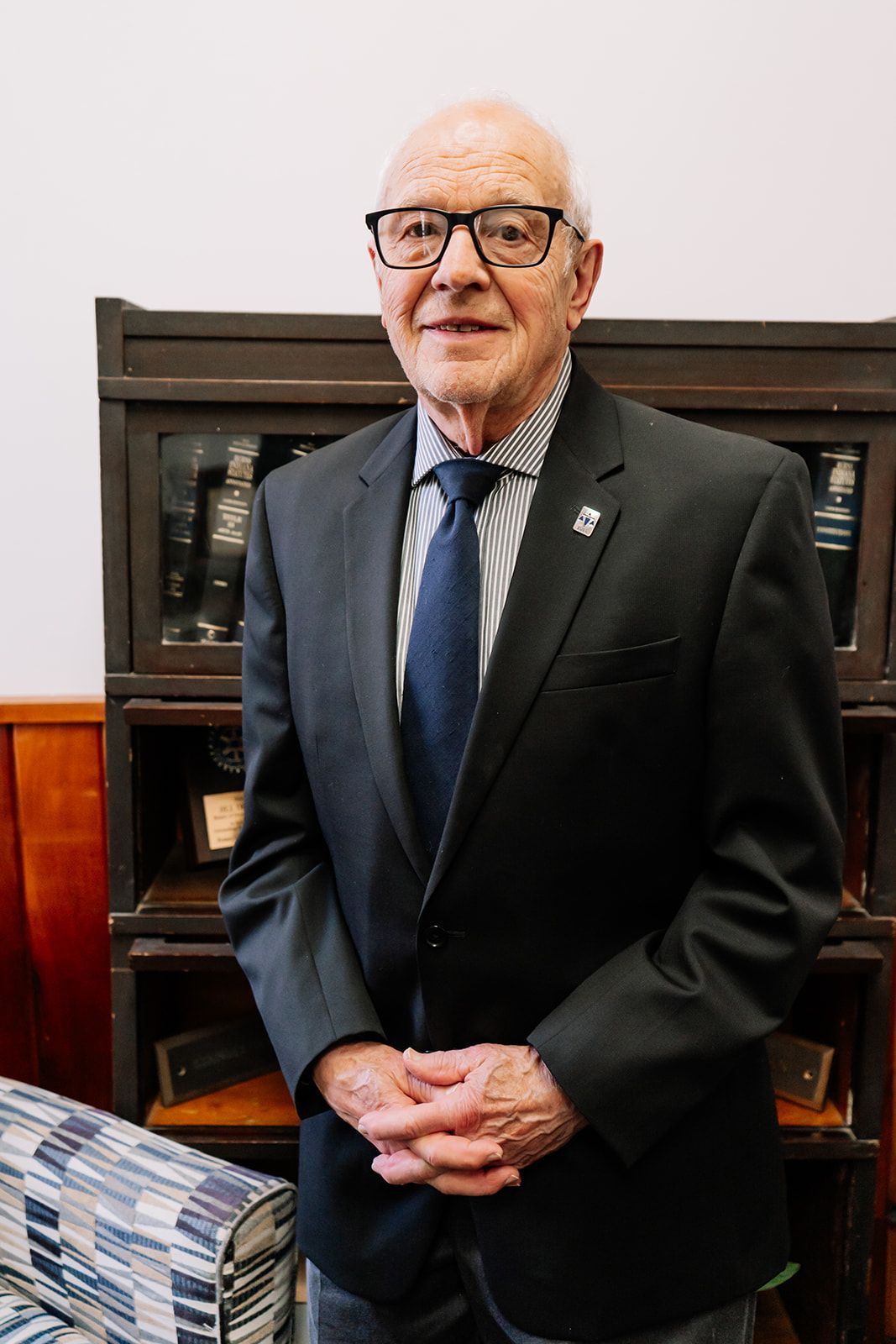 A man in a suit and tie is standing in front of a bookshelf.