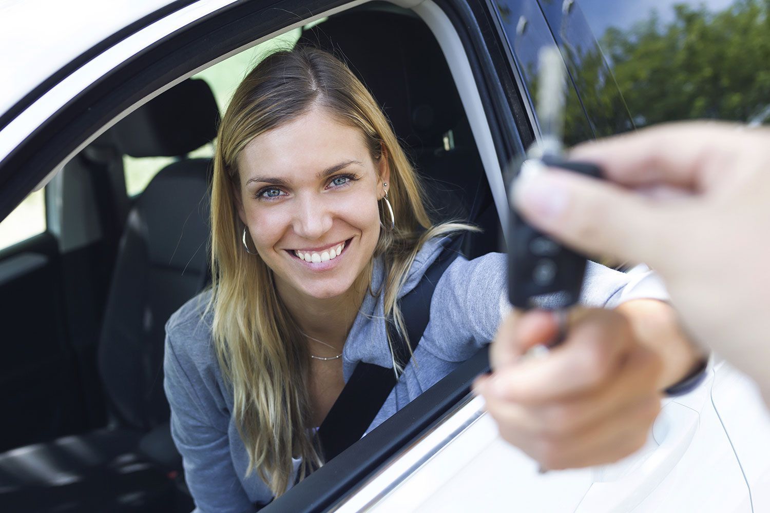 Un autista sorridente si scatta un selfie dall'interno di un'auto bianca.