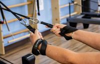 People exercising on pilates reformers in a studio with wooden floors and mirrors