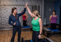Person balancing on a reformer Pilates machine in a gym studio with wall posters in the background
