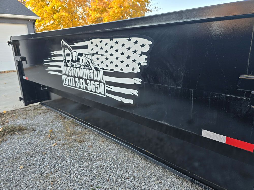 Black dump trailer with American flag design and business name.