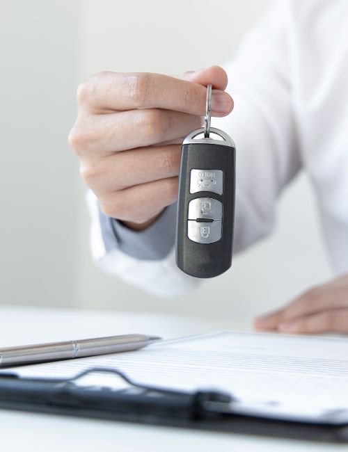 a finance broker is holding a car key over a clipboard