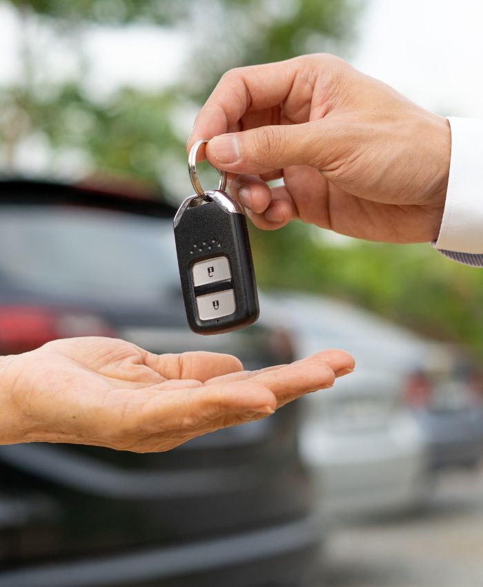 a person is handing a car key to another person - finance broker gold coast