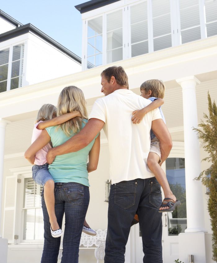 a family standing in front of a white house - home loans gold coast