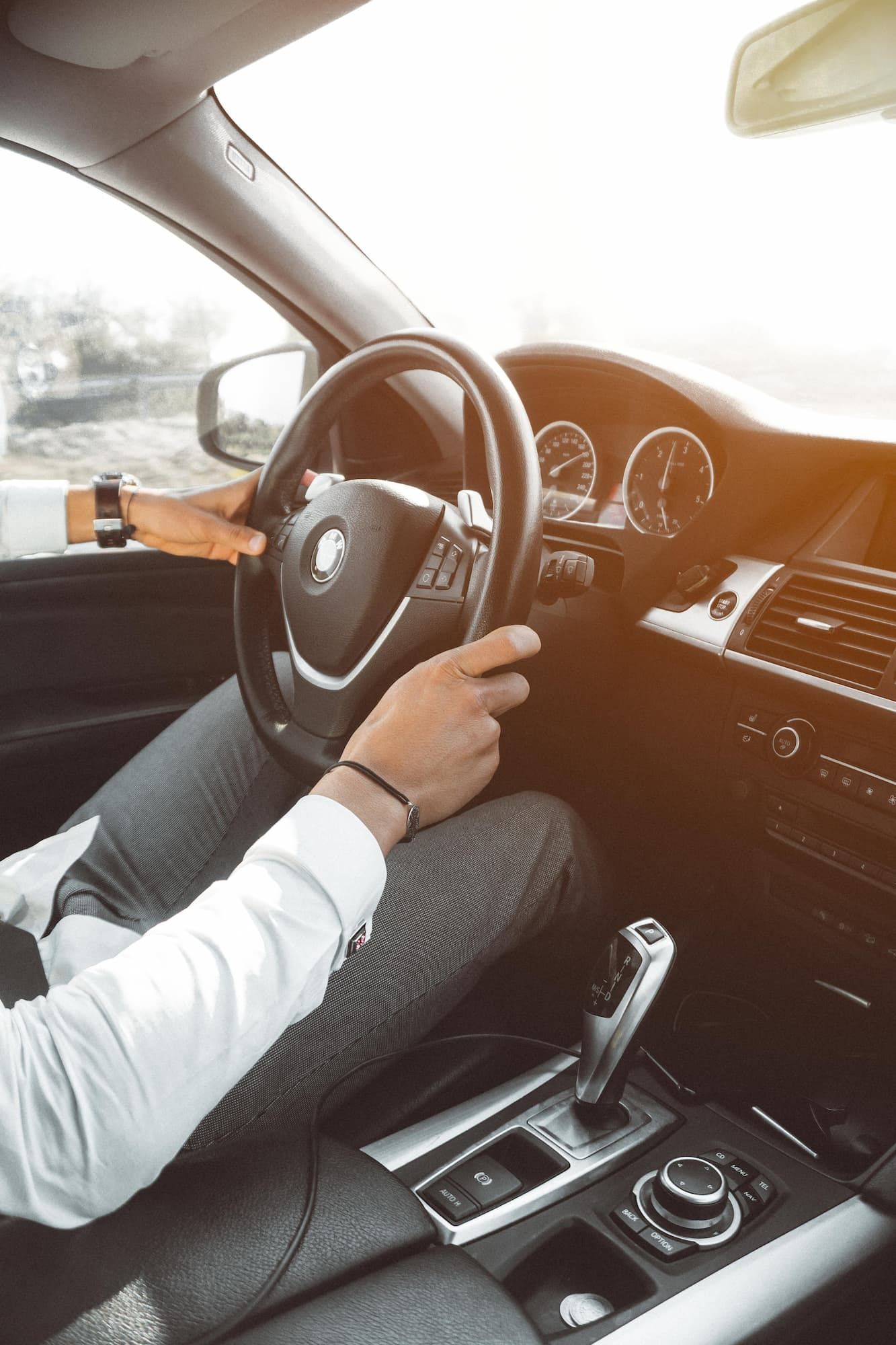 a man is driving a car with a bmw logo on the steering wheel - car loans gold coast