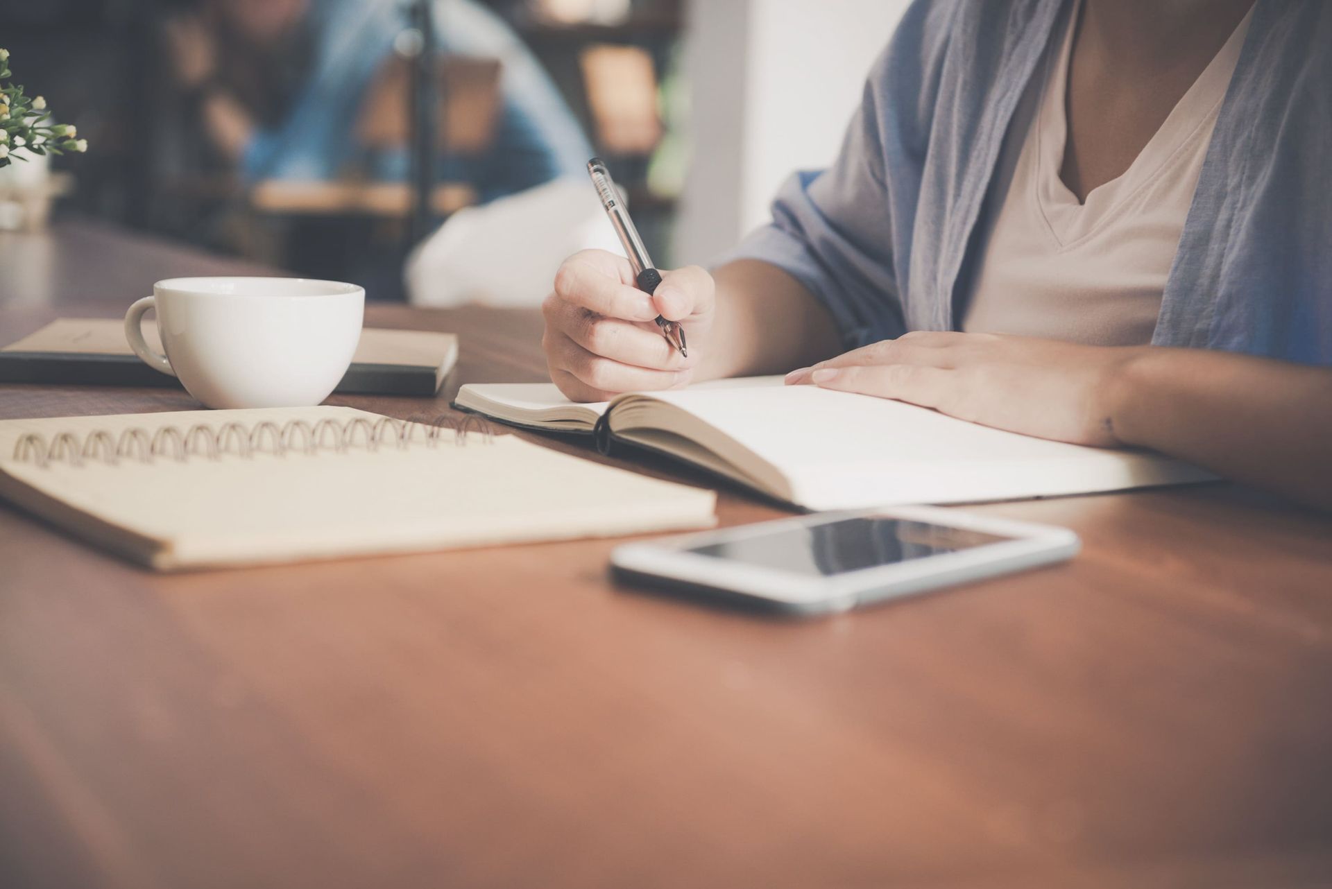 a woman sits at a table writing in a notebook - smsf loan
