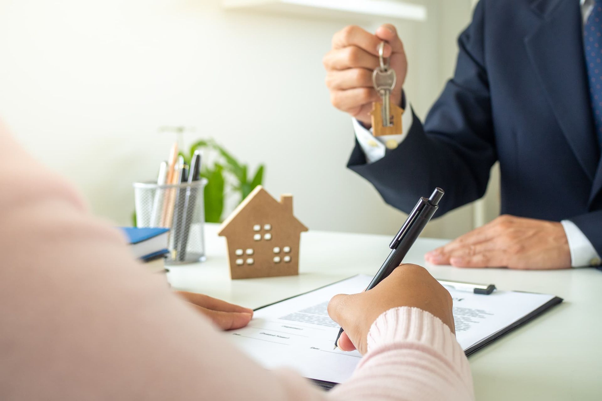 a woman is signing a document while a man holds a key