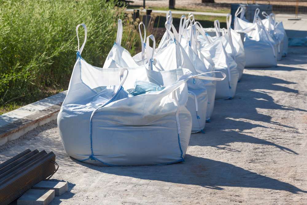 A Row Of White Bags Sitting On Top Of A Dirt Road — HKL Landscape Supplies in Wingham, NSW