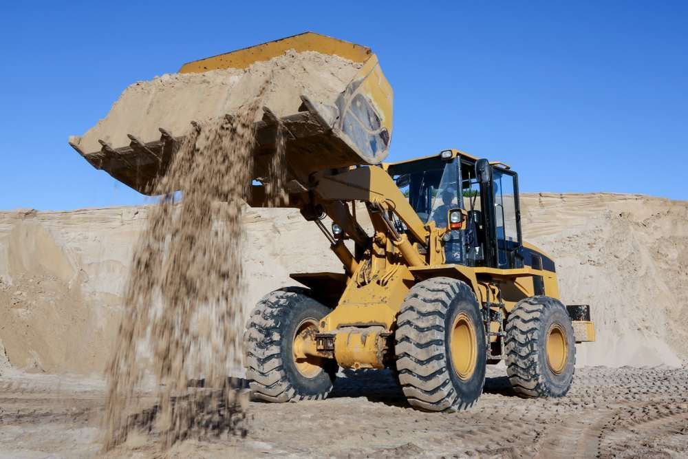 A Bulldozer Is Pouring Sand Into A Pile — HKL Landscape Supplies in Hallidays Point, NSW