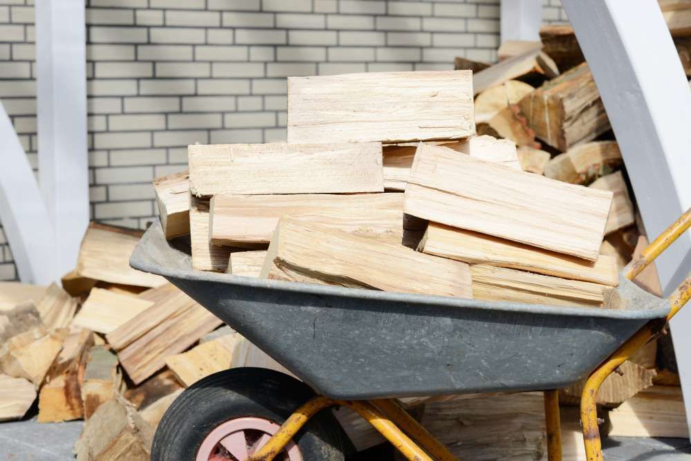 A Wheelbarrow Filled With Wood Is Sitting Next To A Pile Of Wood — HKL Landscape Supplies in Hallidays Point, NSW