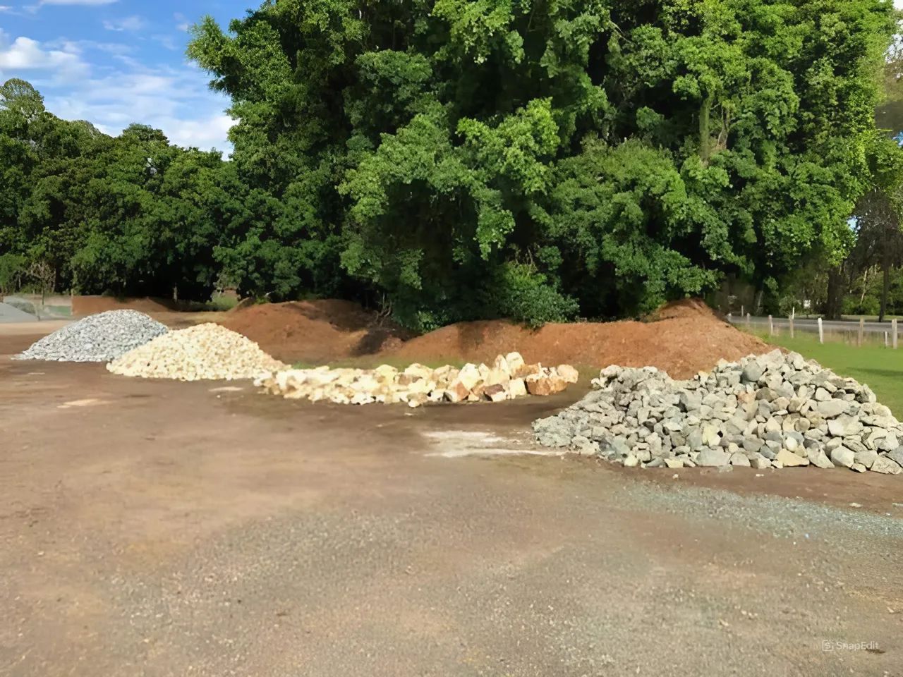 A Pile of Rocks and Dirt in a Field With Trees in the Background — HKL Landscape Supplies in Gloucester, NSW