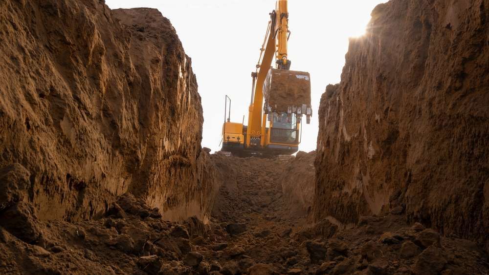 A Yellow Excavator Is Digging A Hole In The Ground — HKL Landscape Supplies in Hallidays Point, NSW