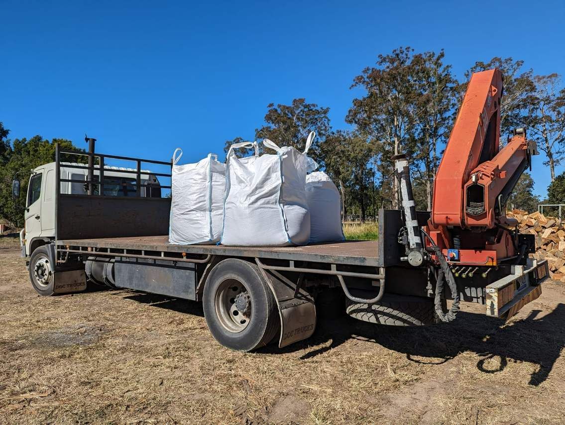 A Truck With a Crane Attached to It is Parked in a Field — HKL Landscape Supplies in Nabiac, NSW