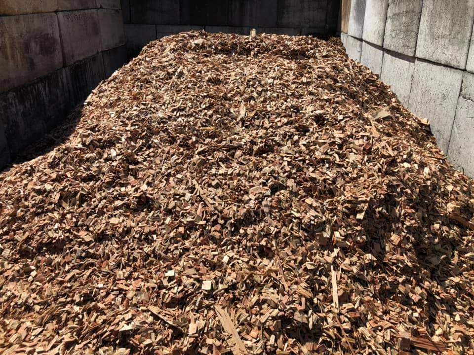 A Pile of Wood Chips is Sitting in Front of a Brick Wall — HKL Landscape Supplies in Coolongoolook, NSW