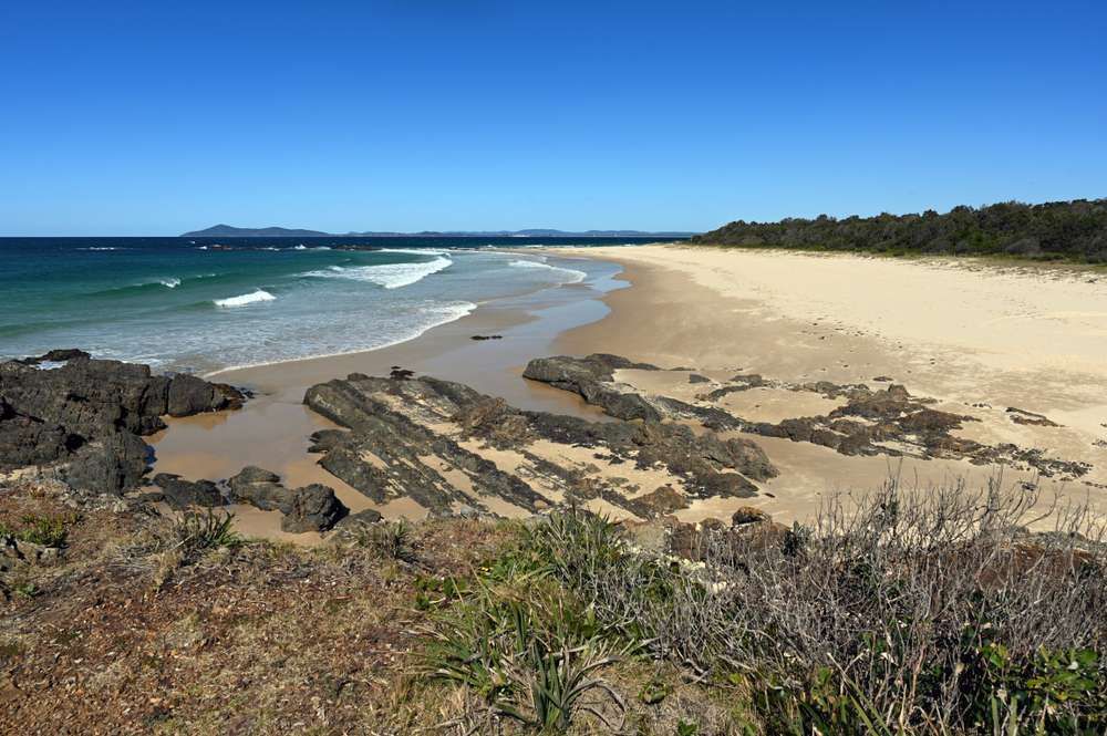 A Beach With A Lot Of Rocks On It And A Blue Sky — HKL Landscape Supplies in Hallidays Point, NSW