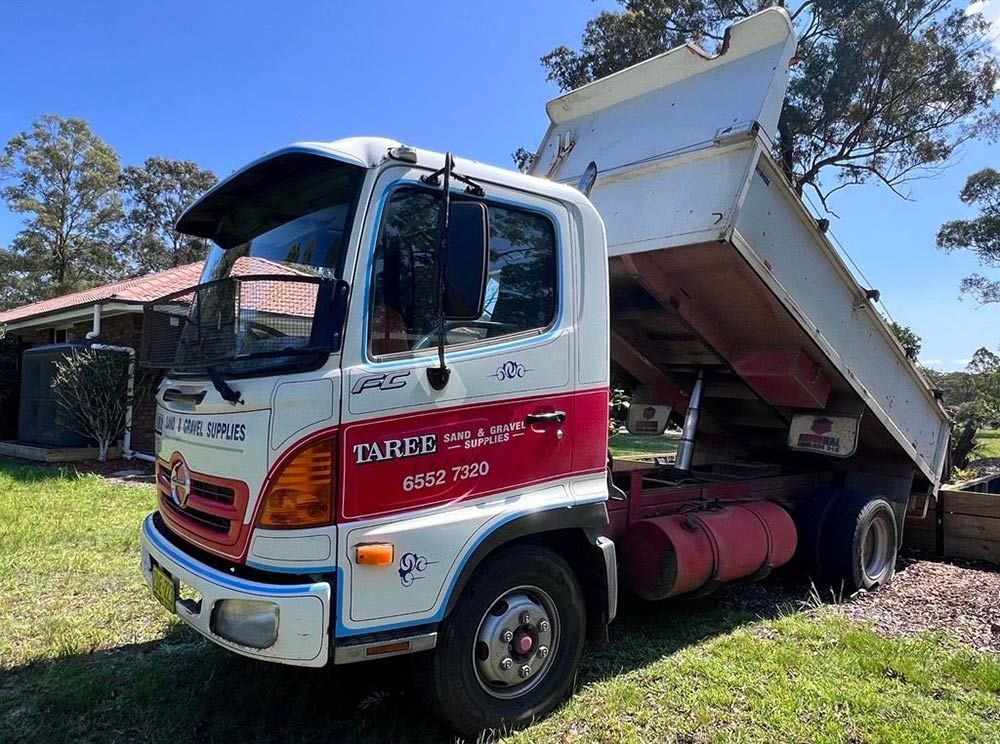 A Dump Truck is Parked in the Grass in Front of a House — HKL Landscape Supplies in Coolongoolook, NSW