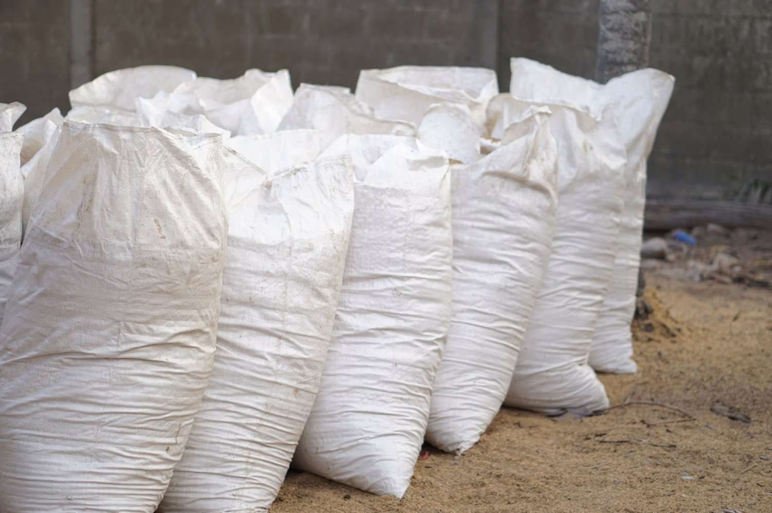 A Bunch Of White Bags Sitting On Top Of A Pile Of Sand — HKL Landscape Supplies in Hallidays Point, NSW