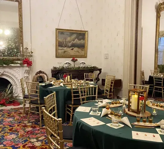 Elegant dining room with green tablecloths, gold chairs, a fireplace, and floral carpet.