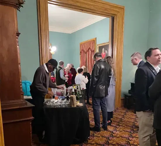 Guests mingling at a formal indoor reception beside a buffet table in a blue room