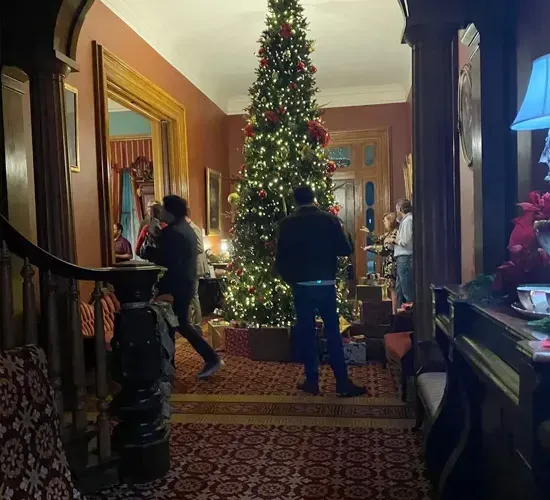 People standing in a decorated hallway beside a tall Christmas tree