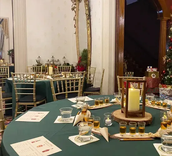Elegant dining room with green tablecloths, gold chairs, and candlelit tables set for an event.