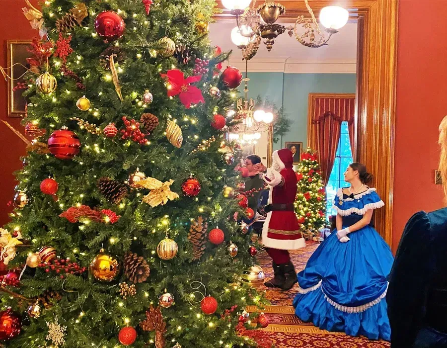 Decorated Christmas tree beside costumed figures in a festive room