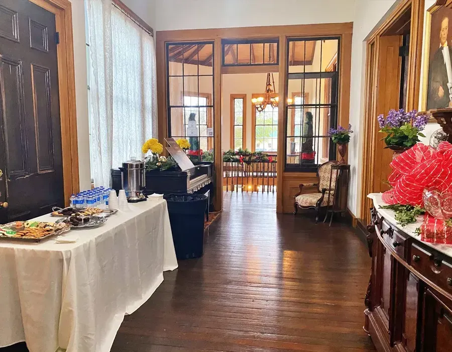 Elegant hallway with tables of food and flowers leading into a sunlit room