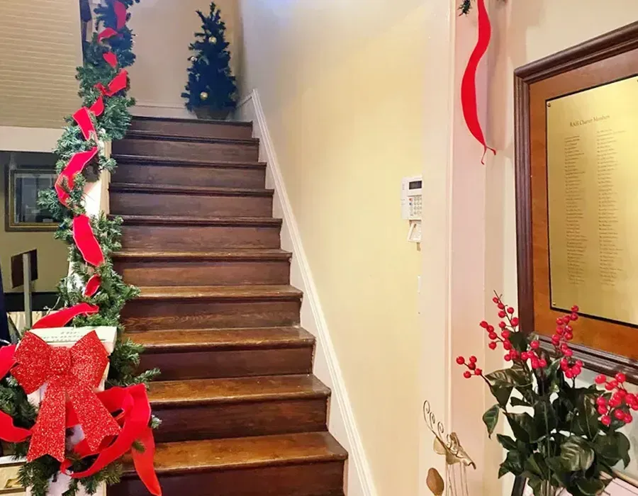 Decorated indoor staircase with red and green holiday garlands and a wreath