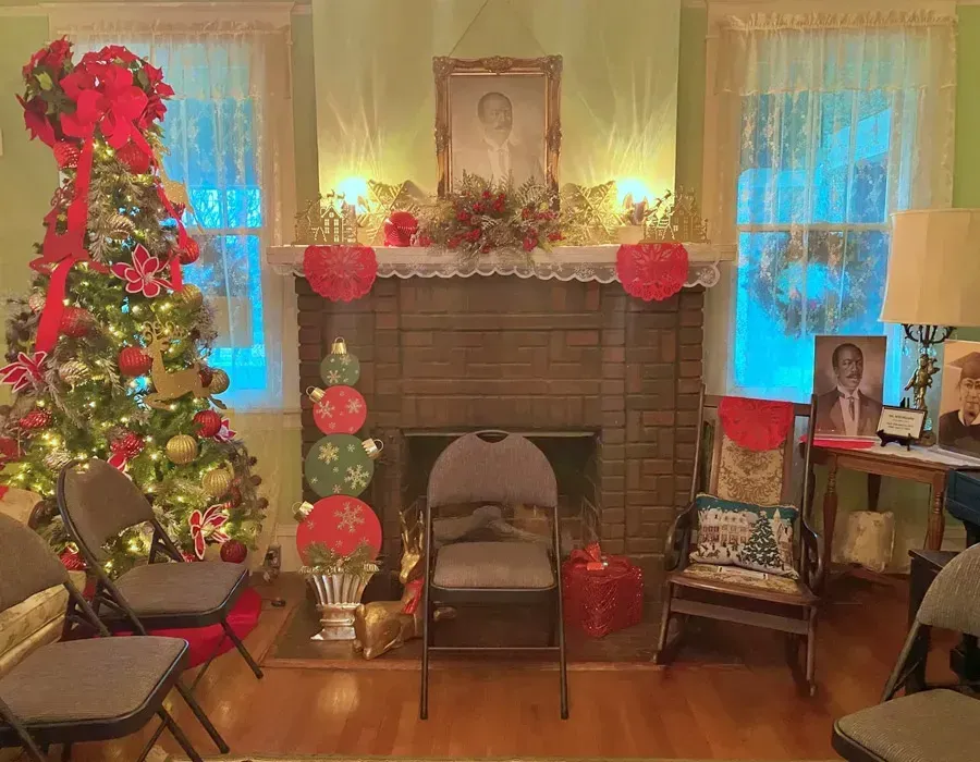 Cozy living room with a decorated Christmas tree, garlands, lights, and a fireplace mantel centerpiece