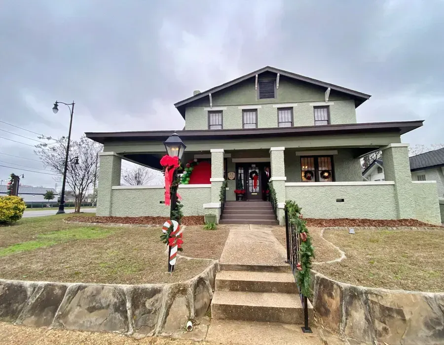 Front view of a gray house with porch, stone steps, and red holiday decorations