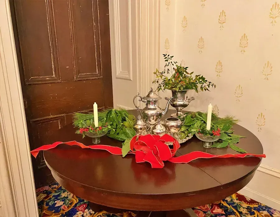 Holiday table display with red ribbon, candles, silver candelabra, and greenery in a hallway