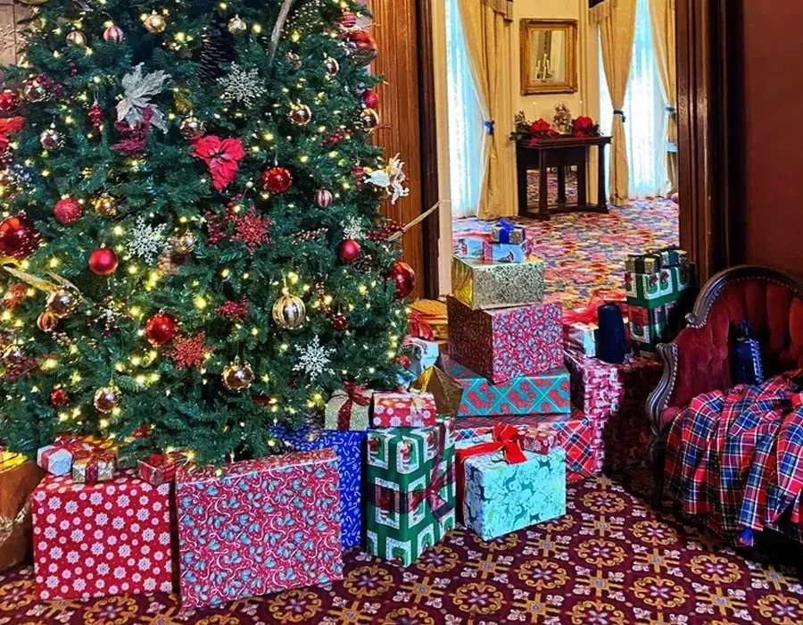 Decorated Christmas tree beside wrapped presents in a festive living room