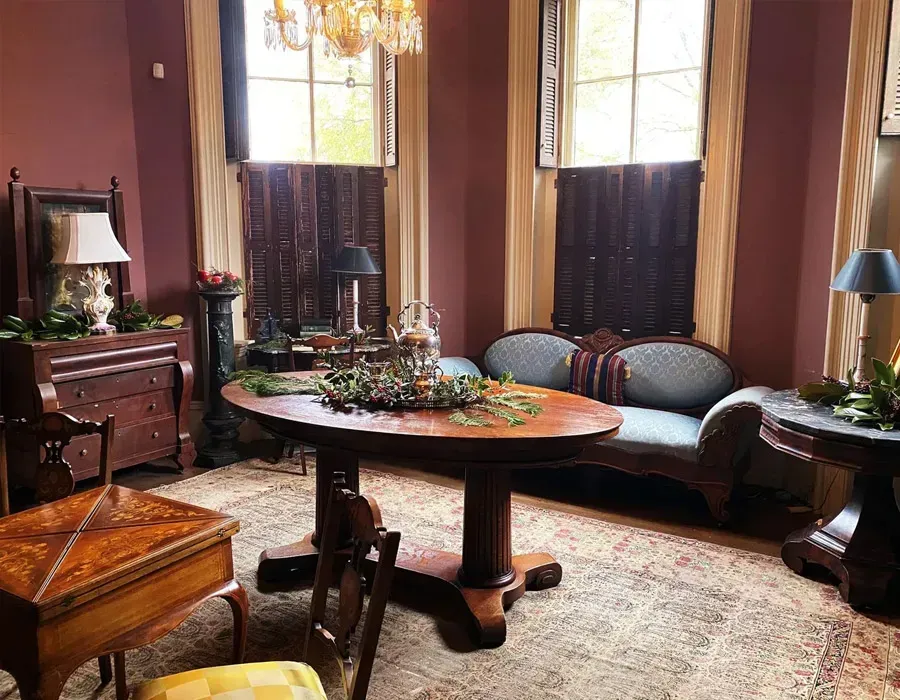 Elegant vintage sitting room with dark wood furniture, large windows, and a round table on a patterned rug
