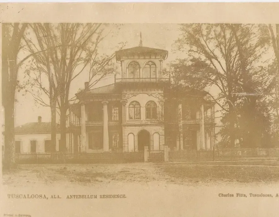 Sepia historic mansion with ornate tower and bare trees in the foreground