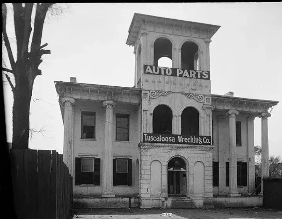 Old storefront with “AUTO PARTS” and “Tennessee Wrecking Co.” signs on a quiet street.