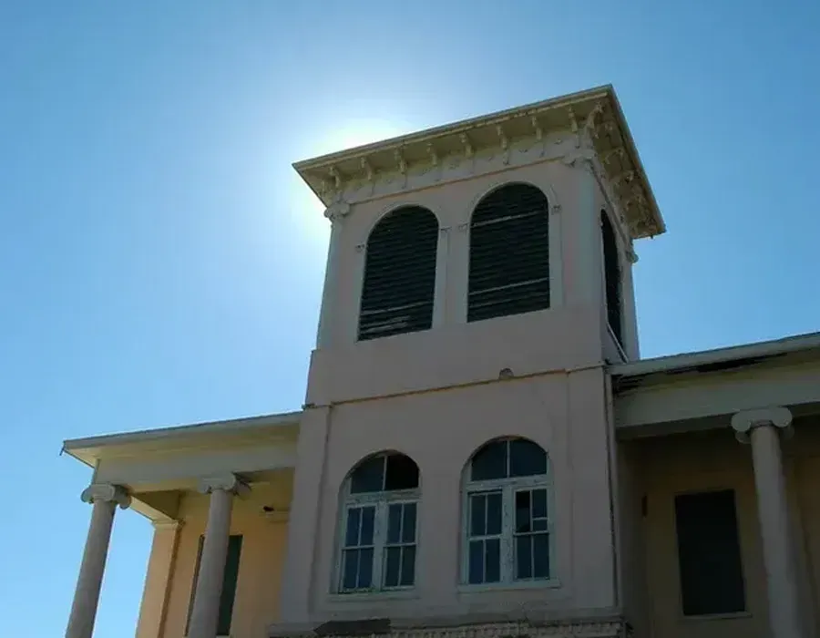 White building tower with arched windows against a bright blue sky