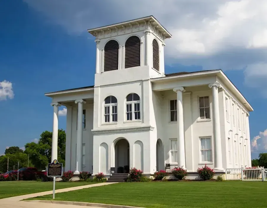White historic church with tall columns and bell tower under a blue sky
