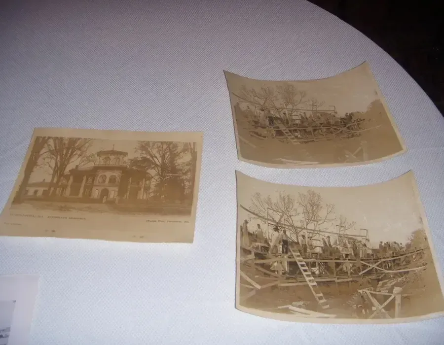 Three old sepia photographs laid on a surface, showing buildings and a rural scene.