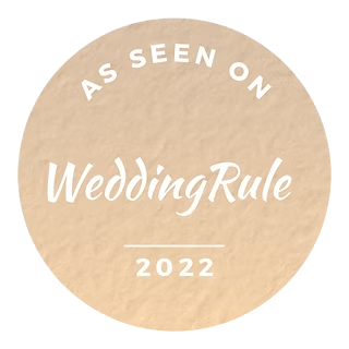 A beige circular badge featuring the white text 