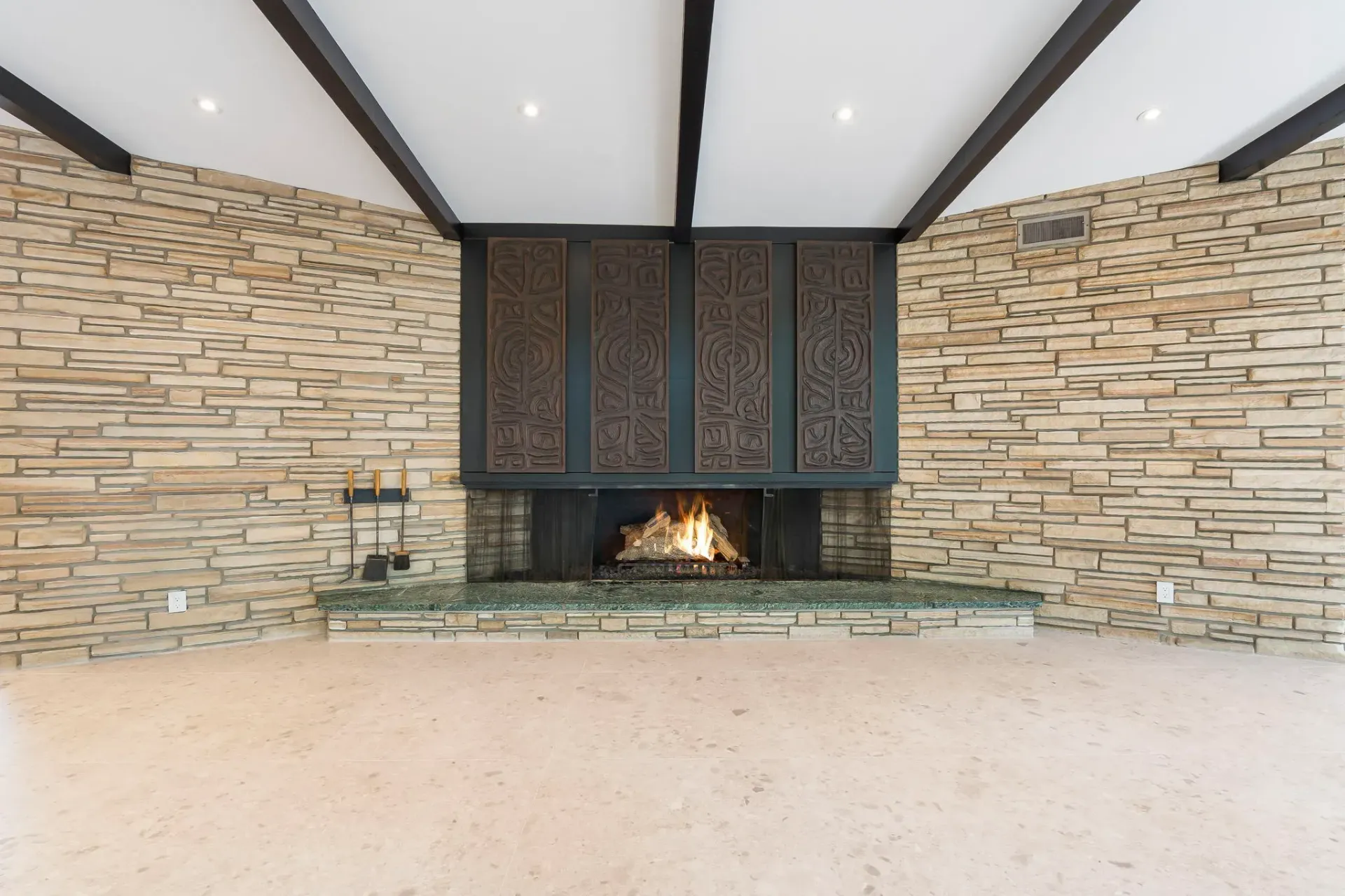 Modern stone fireplace with dark wood screen and lit fire in a vaulted room