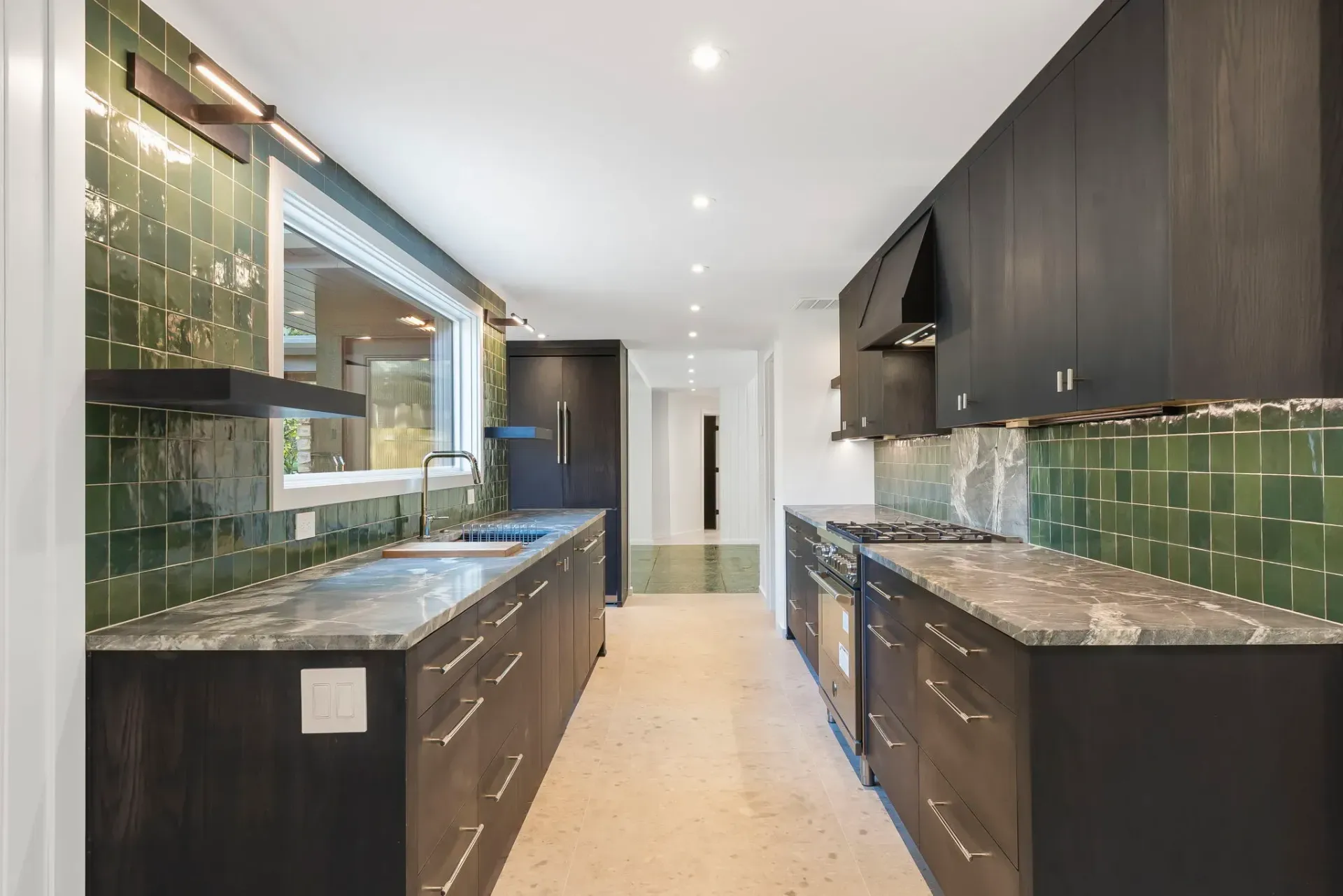 Modern kitchen with dark cabinets, green tile backsplash, and long granite countertops