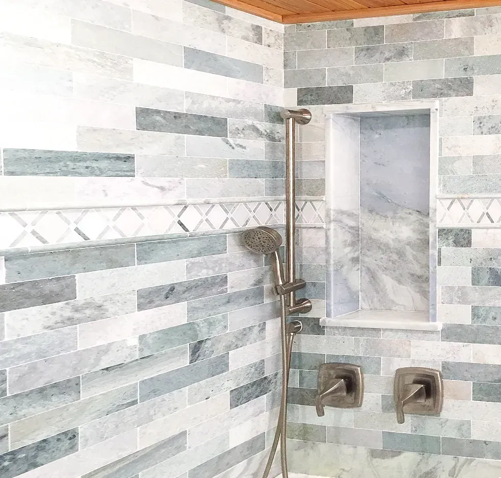 Modern tiled shower with rain showerhead, niche shelf, and dual square control valves