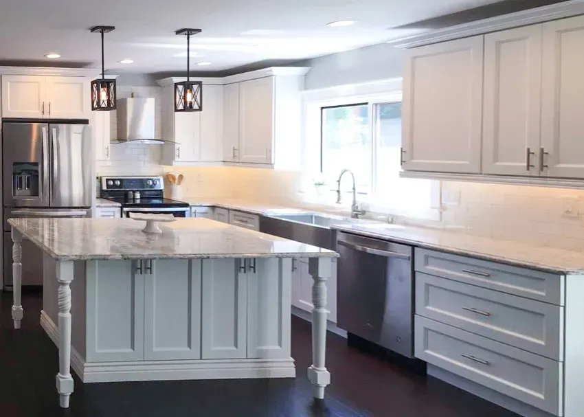 Bright white kitchen with marble island, stainless appliances, and pendant lights