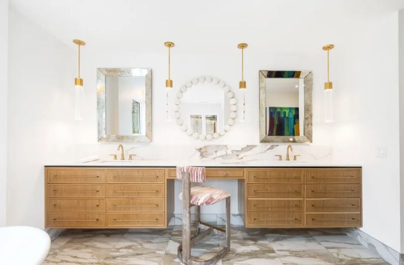 Bright modern double vanity bathroom with wood cabinets, gold fixtures, and large mirrors
