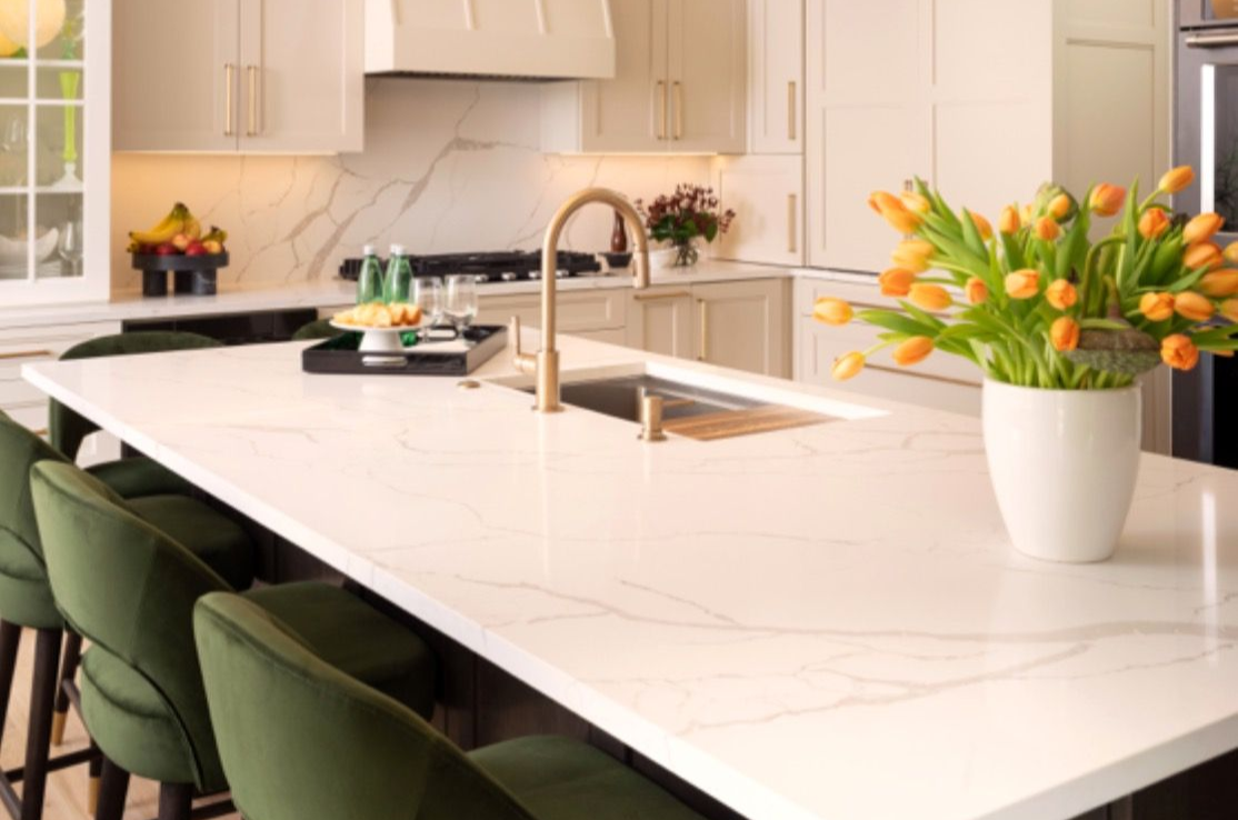 Modern kitchen with white island, green stools, and a vase of orange tulips