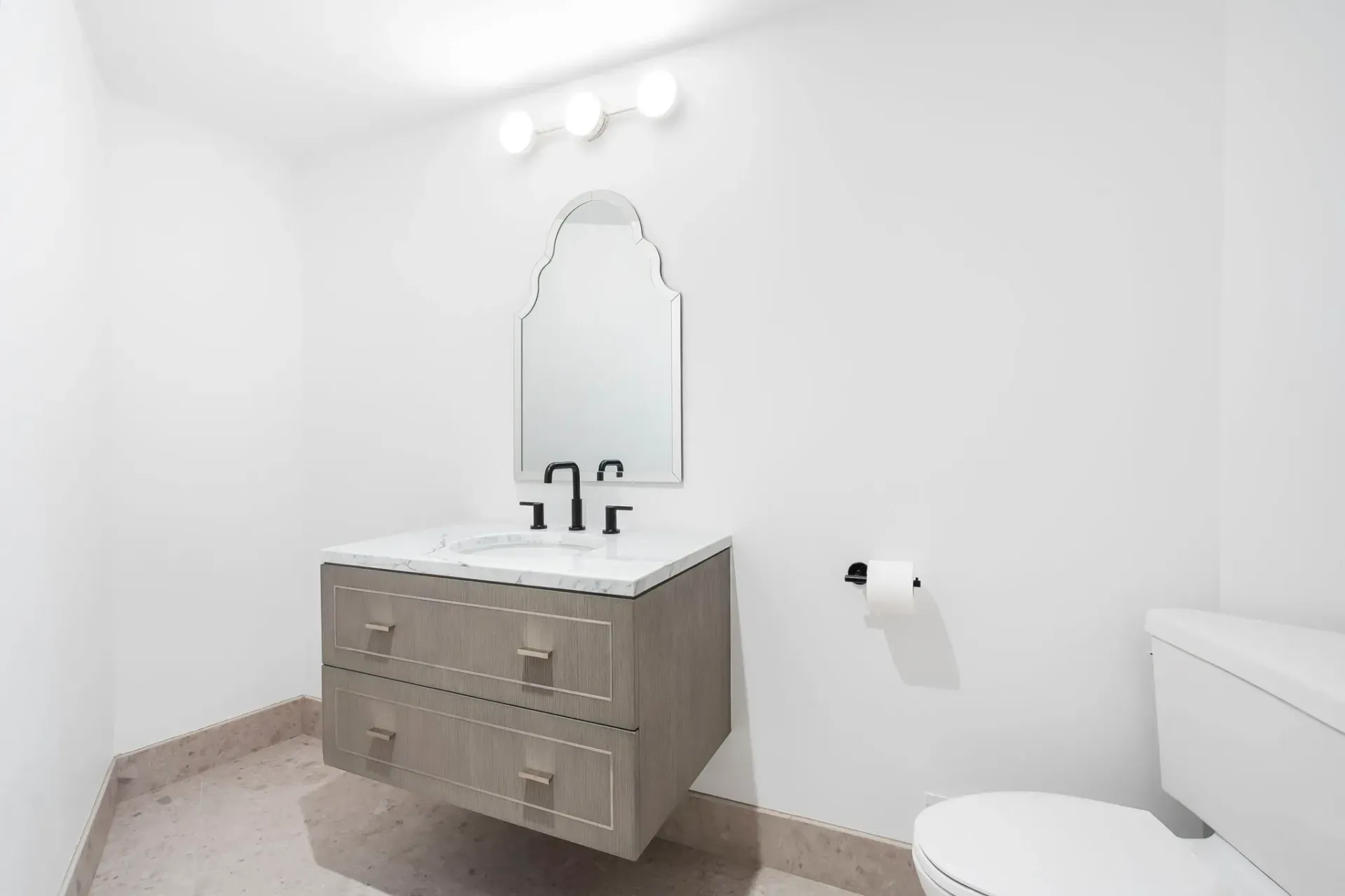 Bright white bathroom with gray vanity, mirror, sink, and toilet.
