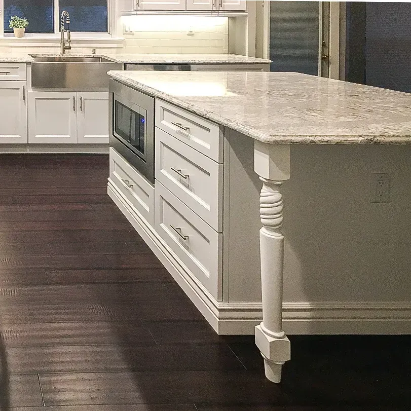 Modern kitchen with white cabinets, dark wood floor, and a large stone island countertop