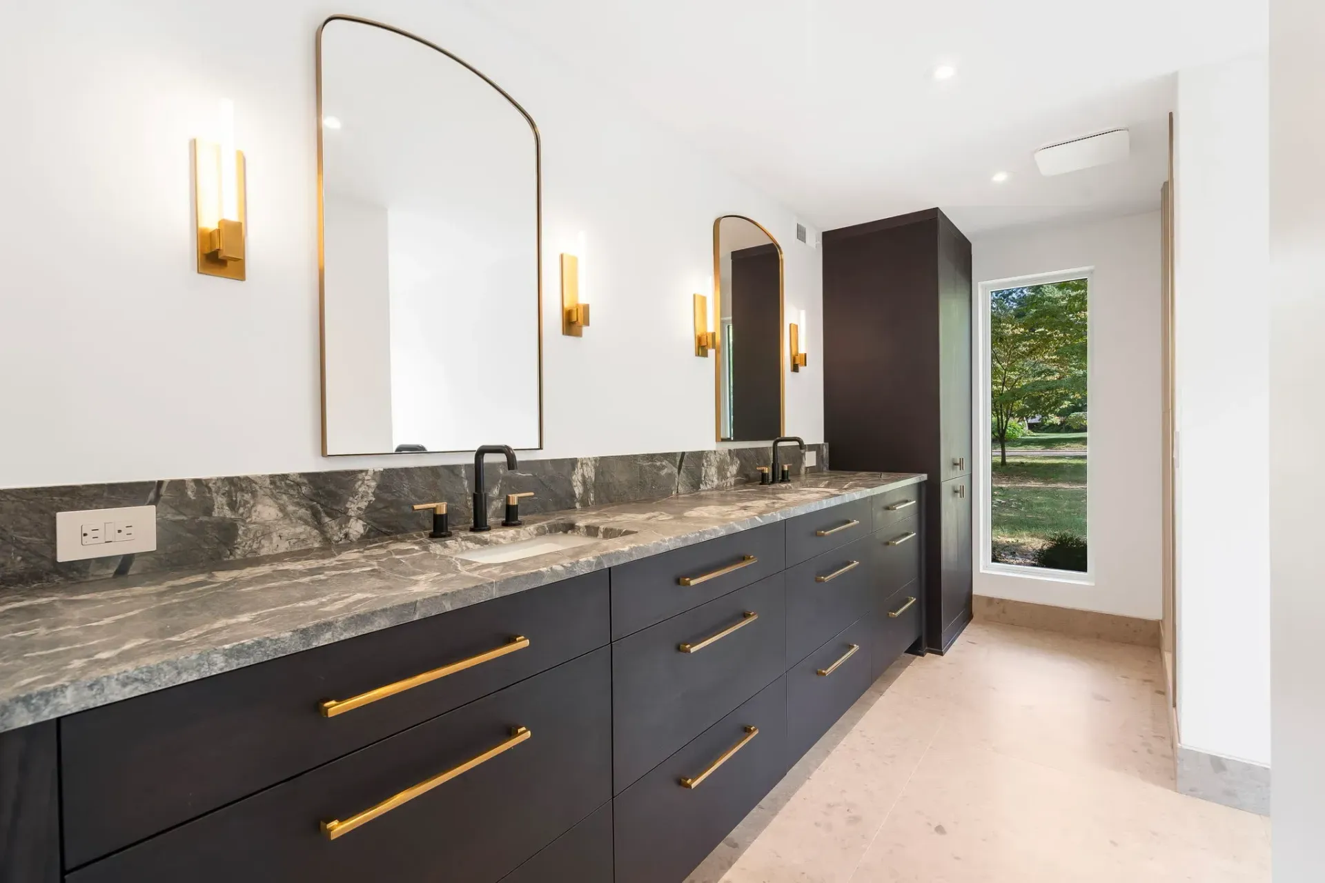 Modern bathroom with long dark vanity, granite countertop, large mirror, and wall sconces